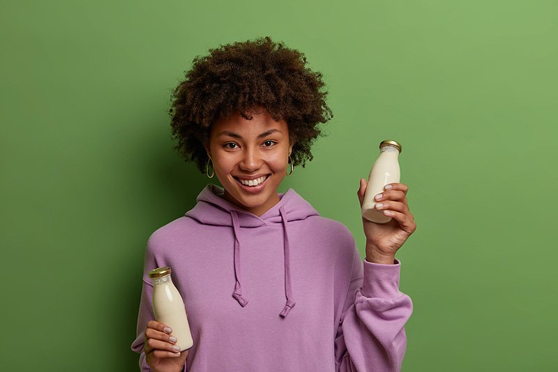 Woman holding bottles with milk and milk alternative.