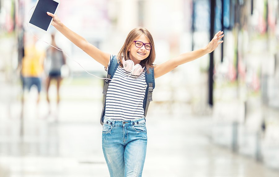 A girl with braces walking down a school hallway.