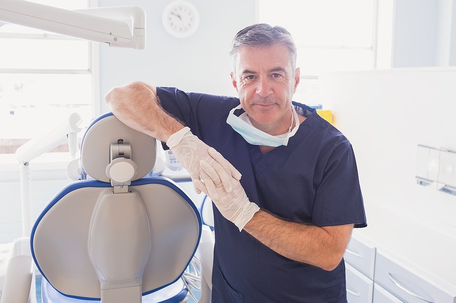 A dentist leans against an operatory chair.